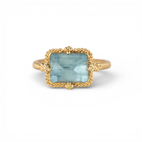 Gold ring with a blue aquamarine gemstone on a white background
