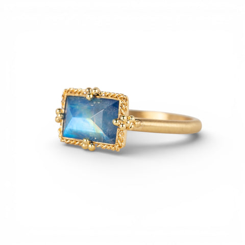 Gold ring with a blue moonstone on a white background