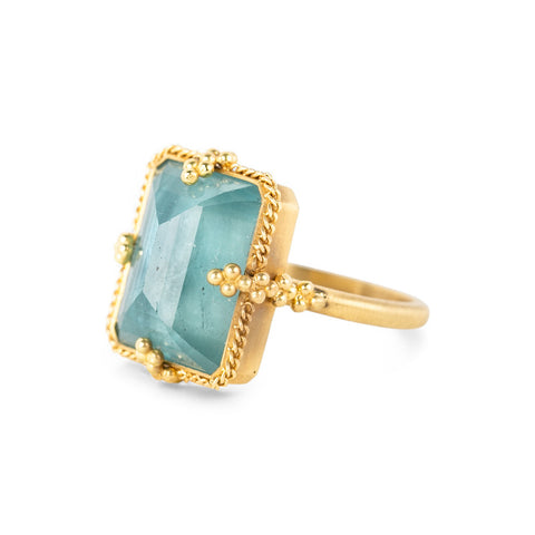 Gold ring with a large aquamarine gemstone on a white background