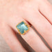 Gold ring with a large aquamarine gemstone on a person's hand