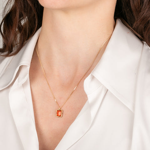 Gold necklace with a fire opal gemstone on a person
