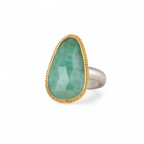Ring featuring an emerald gemstone set in an 18k gold bezel with a silver band