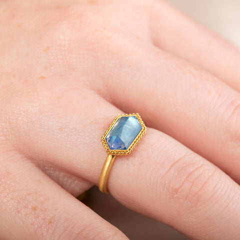 Gold ring with a moonstone gemstone on a person's finger