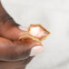 Hand holding a gold ring with an Oregon sunstone gemstone on a light background