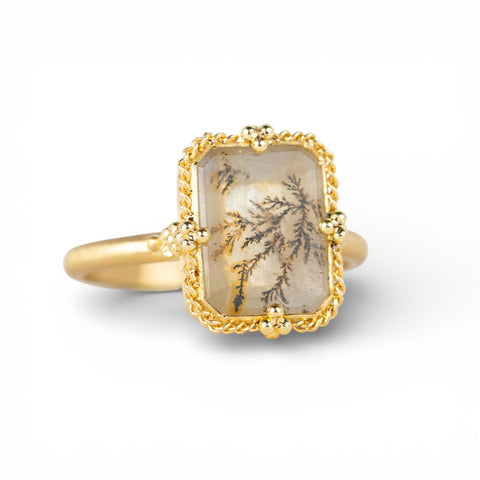 Gold ring with a rectangular dendritic quartz stone on a white background