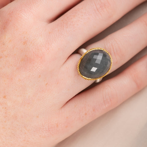 Ring with gray quartz stone, gold bezel and silver band on a hand