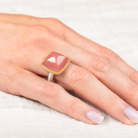 Gold and silver ring with pink guava quartz stone on a hand