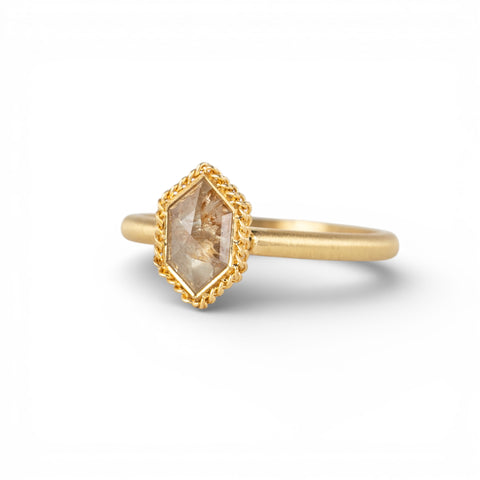 Gold ring with a hexagonal diamond stone on a white background