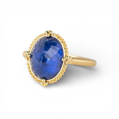 Gold ring with a blue tanzanite gemstone on a white background