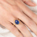 Gold ring with a blue tanzanite gemstone on a hand against a neutral background