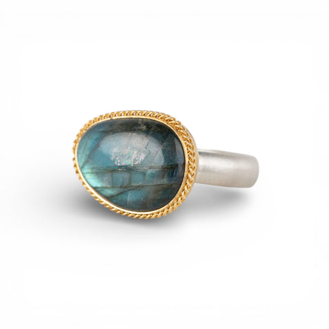 Ring with a gold bezel, silver band and labradorite stone on a white background