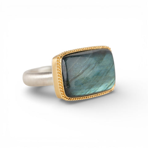 Gold and silver ring with a rectangular labradorite stone on a white background