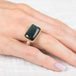 Gold ring with a labradorite stone on a hand against a white background