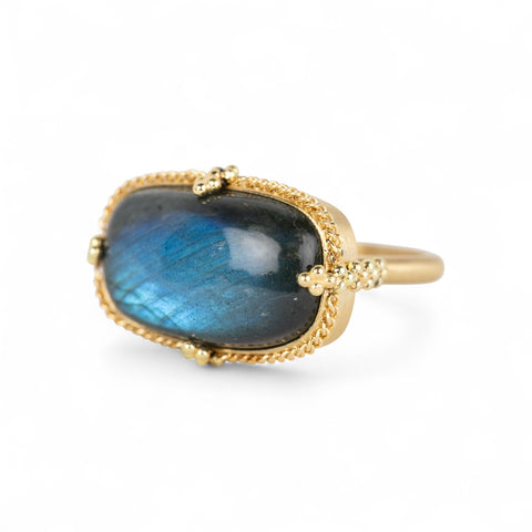 Gold ring with a labradorite gemstone on a white background
