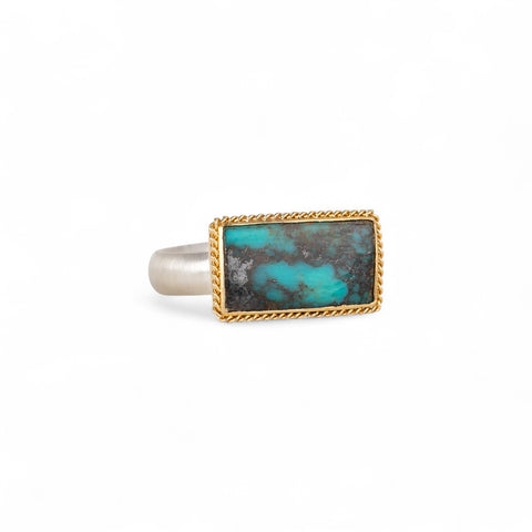 Turquoise ring with gold bezel and sterling silver band on white background