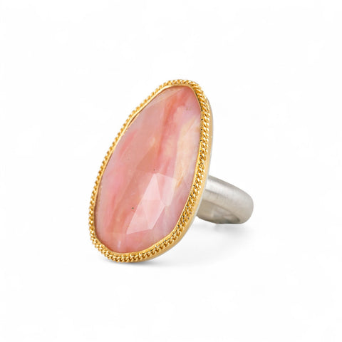 Handcrafted ring with rhodochrosite stone, gold setting and silver band on a white background