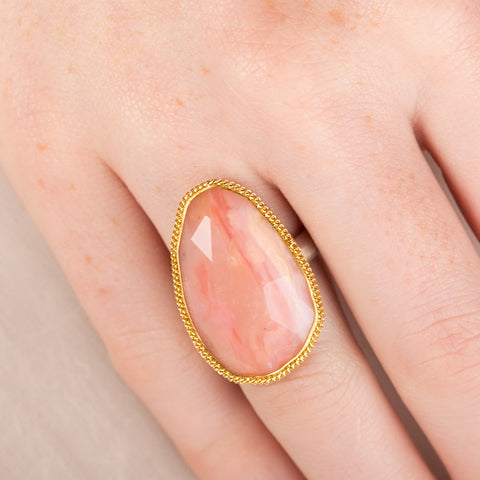 Handcrafted ring with rhodochrosite stone, gold setting and silver band on a hand