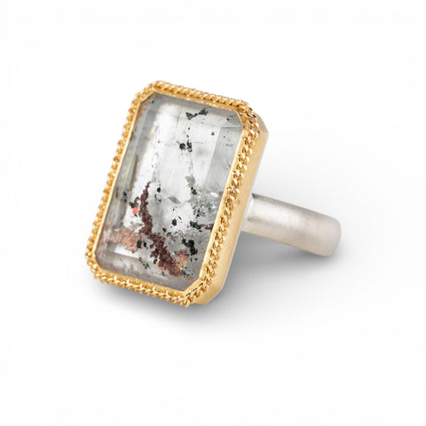 Ring with gold bezel, silver band and lodolite quartz stone on a white background