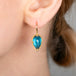 Close-up of a London blue topaz earring with gold setting worn by a person.