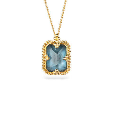 A gold necklace featuring a london blue topaz stone set in an 18k gold bezel, against a white background