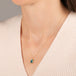 A gold necklace featuring a london blue topaz stone set in an 18k gold bezel, worn on a person's neck.