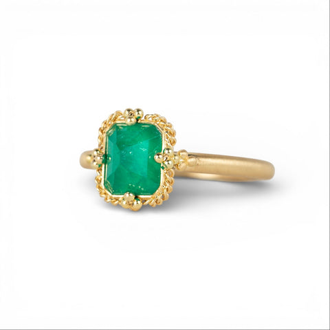 Gold ring with an emerald gemstone on a white background