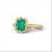 Gold ring with an emerald gemstone on a white background