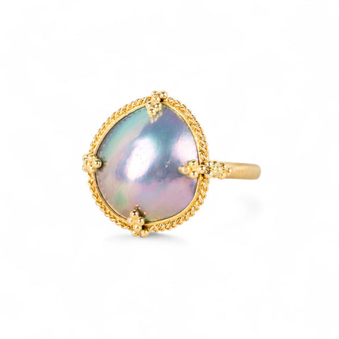 Gold ring with a mabe pearl on a white background