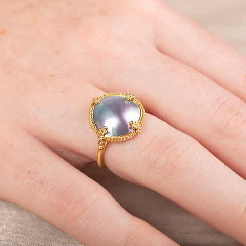 Gold ring with a mabe pearl on a person's finger
