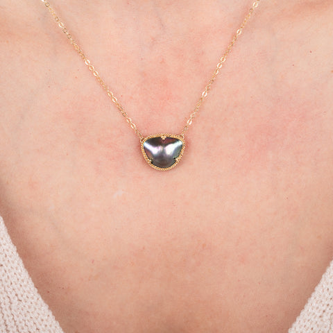Necklace with a mabe pearl pendant on a person's neck