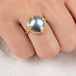 Gold ring with a mabe pearl on a person's finger