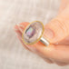 Close up of a person wearing a handmade fine jewelry ring with a Mexican Opal stone, gold bezel and sterling silver band