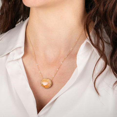 Gold necklace with a large Mexican opal stone on a person