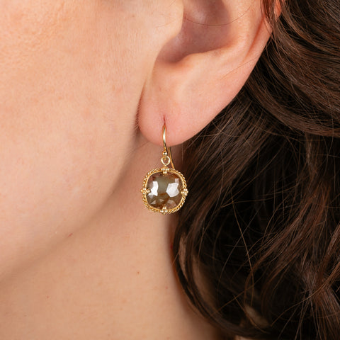 Gold earrings with brown diamonds worn on a person