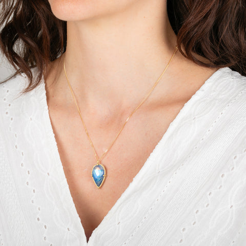 Necklace with a moonstone worn by a person in a white top