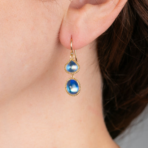 Gold earrings with moonstones worn by a person