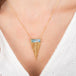 Gold necklace with a moonstone pendant on a person wearing a white top.