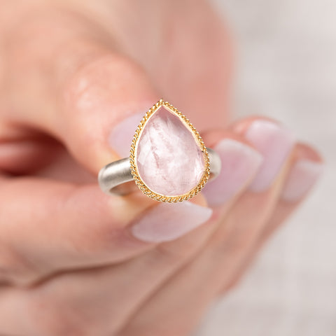 Gold and silver ring with pink morganite teardrop-shaped gemstone held in hand