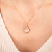Gold necklace with a morganite teardrop pendant on a person's neck