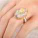 A close up of a person wearing a handmade ring with a Mexican Opal stone set in an 18k gold bezel with a sterling silver band