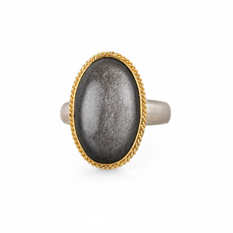 Obsidian ring with gold setting and silver band on a white background
