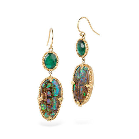 Pair of gold earrings with emerald and opalized wood stones on a white background