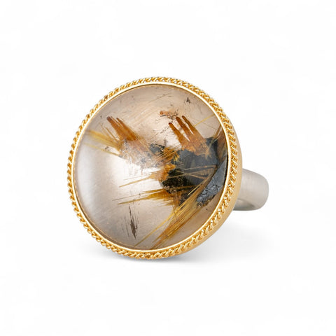 A handcrafted ring with rutilated quartz set in an 18k gold bezel, with a sterling silver band