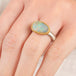 Close up of person wearing a handmade fine jewelry boulder opal ring with an 18k gold bezel and sterling silver band