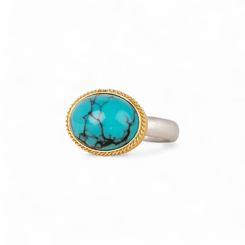 Turquoise ring with gold bezel and sterling silver band on white background