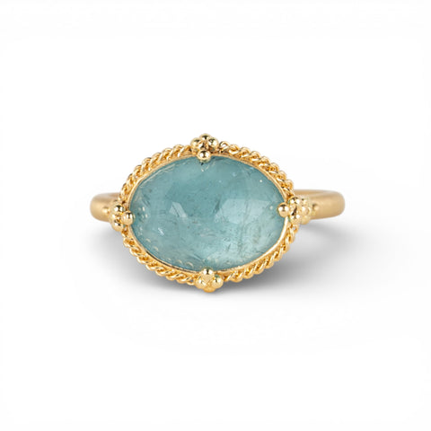 Gold ring with an aquamarine gemstone on a white background