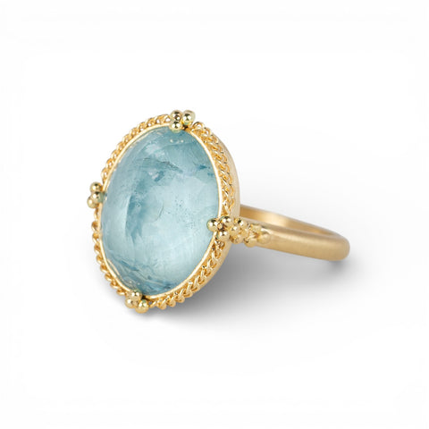 Gold ring with a blue aquamarine gemstone on a white background