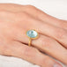 Gold ring with a blue aquamarine gemstone on a person's finger