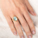 Gold ring with a blue aquamarine gemstone on a person's finger