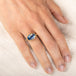 Hand wearing a gold ring with a moonstone gemstone on a light background